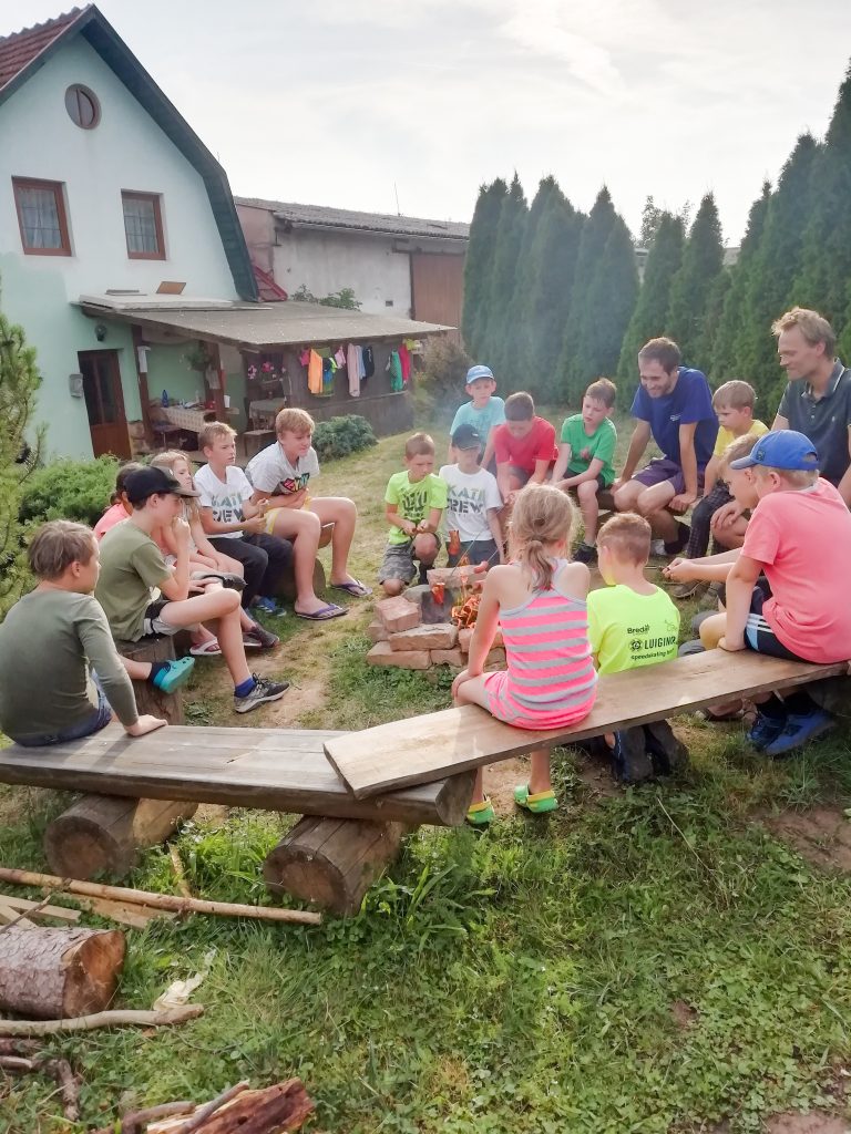 Sezení dětí u ohně a povídání si mezi sebou a s lektory